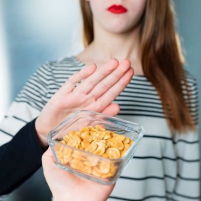 A bowl of peanuts is offered to a young woman who holds up her hand to say no. 